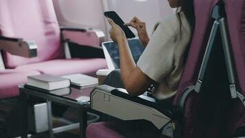 in viaggio e tecnologia. volante a primo classe. bella giovane imprenditori donna utilizzando smartphone mentre seduta nel aereo. video