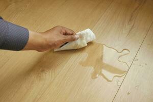 hand wiping spilled tea with paper napkin on floor , photo