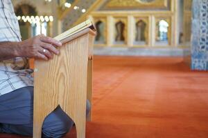 muslim man hand holding Holy book Quran at mosque photo