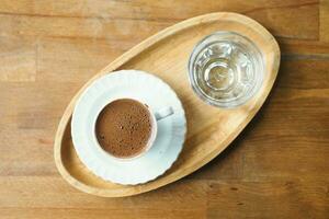 a cup of turkish coffee and glass of water on table photo