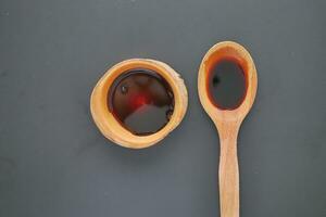 Soy Sauce on a wooden and spoon on black background photo