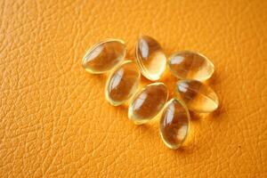 Close up of many vitamin capsule on orange background photo