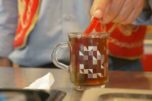 stirring Traditional turkish tea on white table . photo