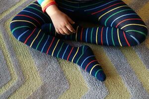 top view of child with Colorful striped socks sitting on carpet photo