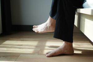 Woman sitting on sofa with feet on carpet at home. photo