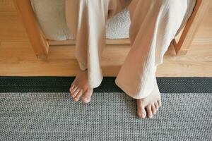 Woman sitting on sofa with feet on carpet at home. photo