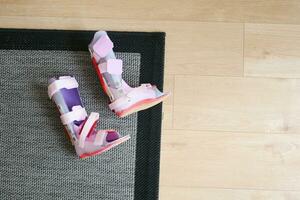 Child cerebral palsy disability legs orthosis shoes on a floor at home photo