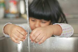 child washing hands at kitchen sink photo