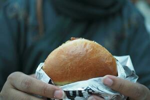 hand holding beef burger on table close up photo