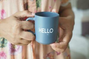 women holding a blue coffee cup with hello word photo