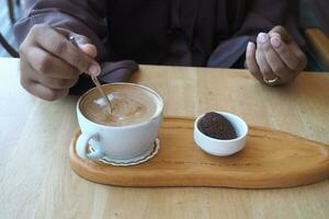 person hand stirring coffee with spoon. photo