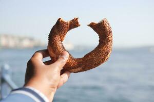 holding a Turkish Bagel Simit against istanbul city background photo