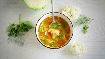 vegetable summer soup with cauliflower in a bowl on a light wooden table video