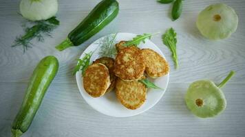 fried vegetable pancakes from squash and zucchini with herbs, on a light wooden table. video