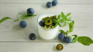 sweet homemade yogurt with fresh plum slices in a glass on a wooden table video