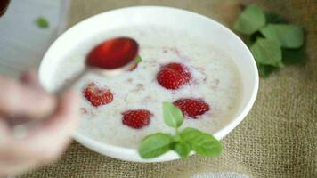 Süss Milch Haferflocken mit Erdbeeren im ein Platte, auf ein hölzern Tisch. video