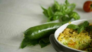 vegetable casserole of patissons, zucchini, carrots in a ceramic form on a light wooden table. video