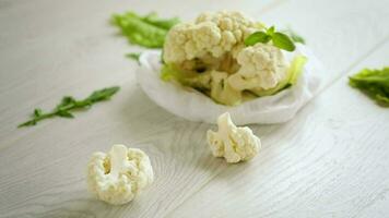 inflorescences of small raw cauliflower on a light wooden table video