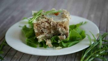 jellied meat with greens and vegetables in a plate on a wooden table video