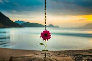 a flower hanging from a chain on the beach. AI-Generated photo