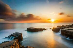 un hermosa puesta de sol terminado el Oceano con rocas y agua. generado por ai foto