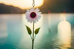 a flower hanging from a chain in front of a lake. AI-Generated photo