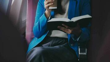 Successful female book editor reading literature during time in airplane before business meeting with writer, confident formally dressed woman enjoying international flight and leisure for novel video