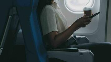 retrato do uma bem sucedido ásia o negócio mulher ou fêmea empreendedor dentro formal terno dentro uma avião senta dentro uma o negócio classe assento e beber café durante voo, relaxar conceito video