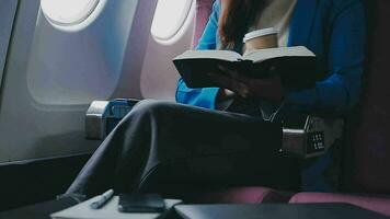 exitoso hembra libro editor leyendo literatura durante hora en avión antes de negocio reunión con escritor, confidente formalmente vestido mujer disfrutando internacional vuelo y ocio para novela video