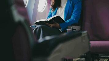 Successful female book editor reading literature during time in airplane before business meeting with writer, confident formally dressed woman enjoying international flight and leisure for novel video