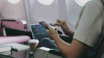 op reis en technologie. vliegend Bij eerste klas. mooi jong zakenmensen vrouw gebruik makend van smartphone terwijl zittend in vliegtuig. video