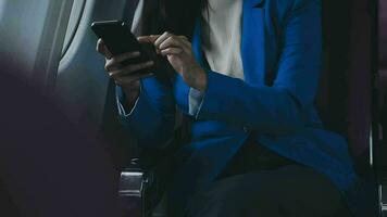 Traveling and technology. Flying at first class. Pretty young businees woman using smartphone while sitting in airplane. video