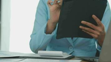 Asian Business woman using calculator and laptop for doing math finance on an office desk, tax, report, accounting, statistics, and analytical research concept video