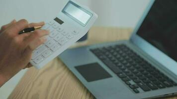 Asian Business woman using calculator and laptop for doing math finance on an office desk, tax, report, accounting, statistics, and analytical research concept video