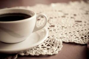 white cup with black coffee on a hand-made tablecloth photo