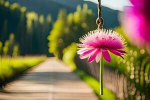 a pink flower hanging from a string in front of a green field. AI-Generated photo