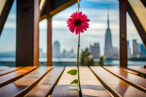 un rosado flor se sienta en un de madera banco en frente de un ciudad horizonte. generado por ai foto