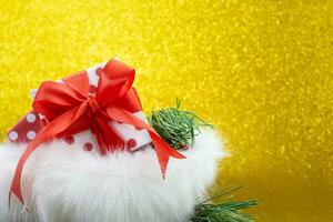 Open fluffy bag with gift box with polka dot and red bow and fir branches on yellow blurred background with soft focus. Christmas, New year, birthday, sale, black Friday. Copy space photo