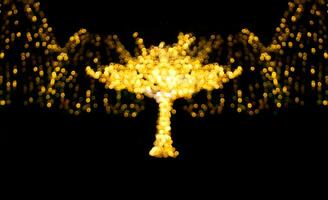 Defocused illuminated tree with blurred lights with garlands on black isolated background. City, holiday lighting. Christmas, New Year, holidays, evening lanterns. Soft focus. Copy space photo