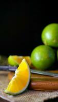 Orange fruit with green peel, half part, and slice with dark mood photography. Vertical, portrait, mobile phone wallpaper photo