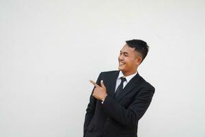 Portrait Young handsome Asian businessman with happy and smiling face finger pointing at copy space isolated on white background photo