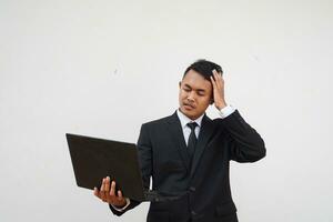 Portrait Young Asian businessman stress with his work hold laptop isolated on white background photo