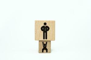 concept of employees working hard for the boss. Employees who work hard to make their boss richer. Wooden cube with a person icon take up a larger dice with a boss icon. Boss slave employee photo