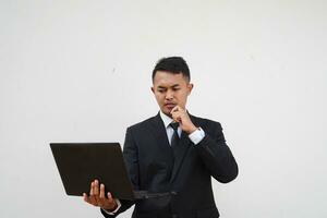 Portrait Young Asian businessman work with laptop while thinking about strategy isolated on white background photo