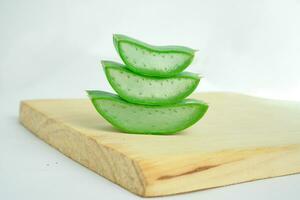 the isolated pile of Aloe Vera pieces on wooden cutting board with  white background photo