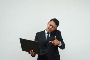 Portrait Young Asian businessman multitasking, calling with mobile phone while working with laptop isolated on white background photo