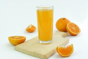 Orange juice with 100 glass with slice, half, and whole orange fruit on a wooden cutting board isolated white background with shadow. Landscape. Horizontal photo