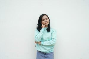 Portrait Indonesian beautiful woman wearing light blue sweater with thinking gesture isolated on white background photo