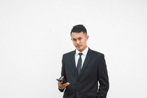 Handsome Asian young businessman using mobile phone with black suit on white background photo