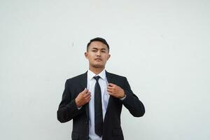 Handsome young businessman straightening his black suit on white background photo